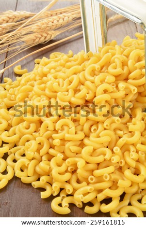 Elbow macaroni noodles spilling out of a glass canister