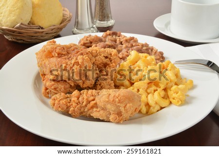 A plate of fried chicken with rice and beans