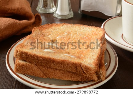Hot buttered whole wheat toast on a rustic wooden table