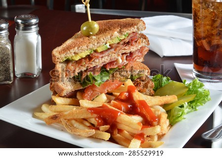 A bacon, lettuce and tomato sandwich with fries and a cola
