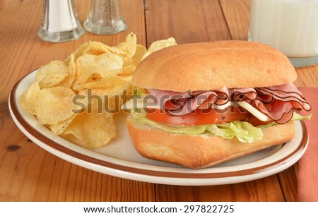 A ham and swiss cheese sandwich with potato chips