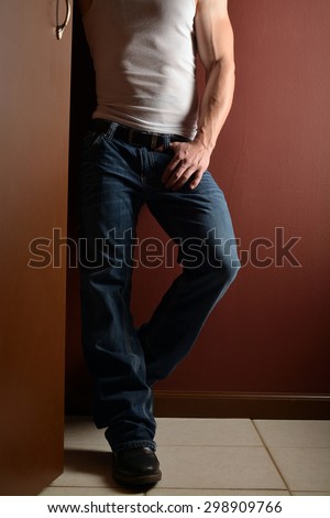 lower body shot of a muscular man in a wife beater and blue jeans