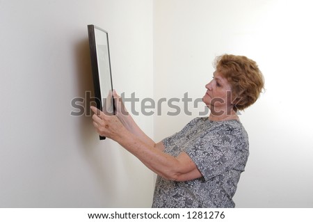 A woman hangs a picture