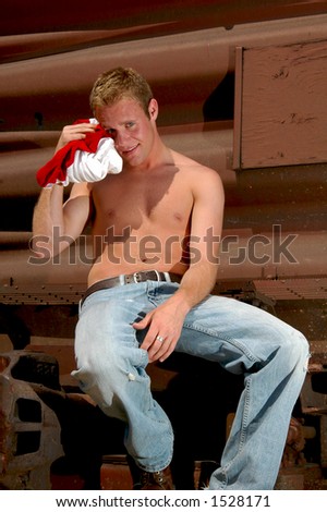A railroad worker wiping sweat from his brow with a shirt