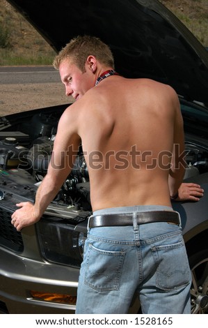 A shirtless man working on a car