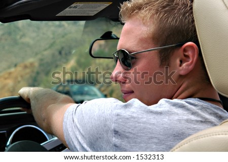 Handsome man driving convertible up a mountain road