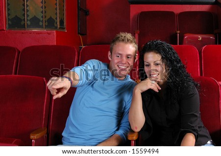 Man pointing something out to woman in movie, concert venue