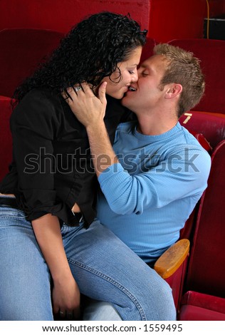 Man and woman kissing in back row of movie theater
