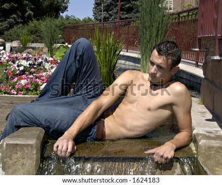 Young man cooling off in a water fountain