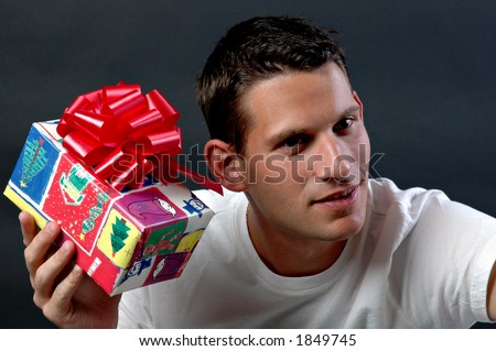 Man shaking a Christmas gift to guess what is in it