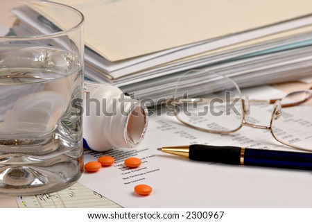 a bottle of aspirin and glass of water by financial statements and bills