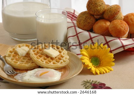 Breakfast of eggs, waffles, muffins and milk