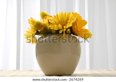 A vase of flowers in front of window curtains