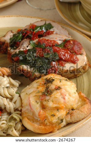A dinner of crab patti melt, pasta salad, and herbed pork