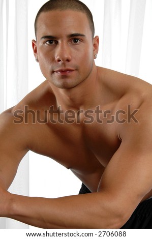 A handsome muscular man leaning in front of the window curtains