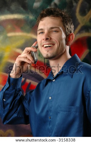 A man talking on a cell phone near a graffiti covered wall