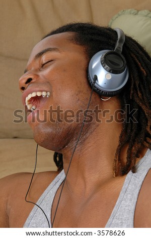 A happy young man singing to the music on headphones
