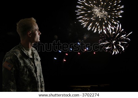 A young soldier watches while fireworks blow in the wind