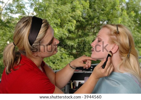 A makeup artist applying blush to a model on location