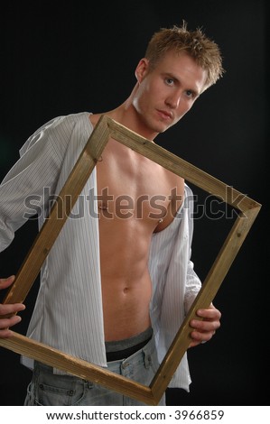 A handsome shirtless man holding a wooden picture frame