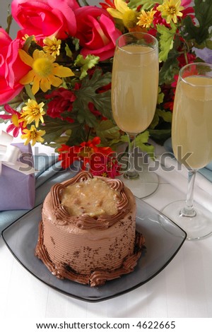 A delicious german chocolate cake on a table with champagen and a bouquet of flowers