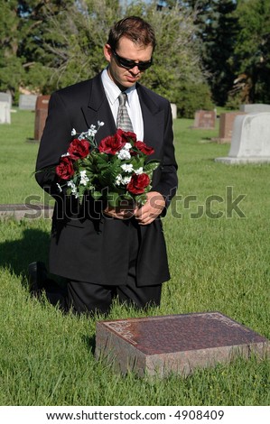 stock-photo-a-man-with-a-bouquet-of-flowers-kneeling-before-a-grave-4908409.jpg