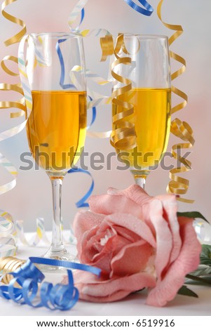 Party ribbon falls onto wine glasses and a rose