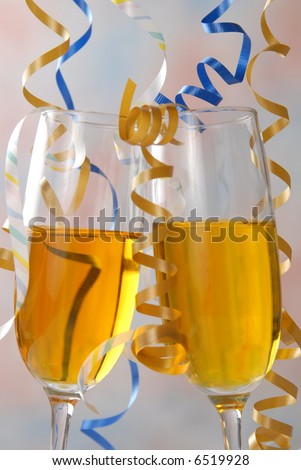 Champagne glasses tipped together in a toast under falling party ribbon