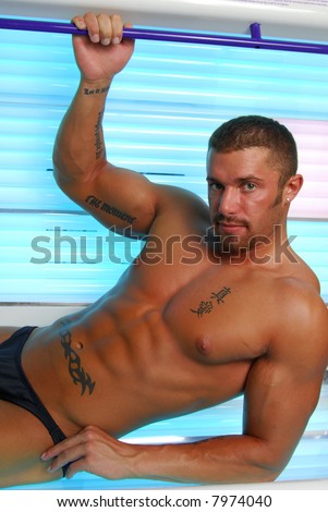 A muscular man laying in a tanning bed