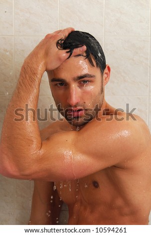 A muscular young man washing his hair in the shower