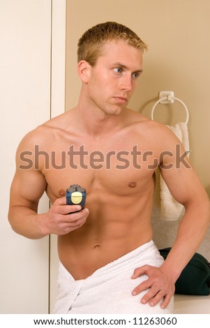 A handsome young man about to shave with an electric razor