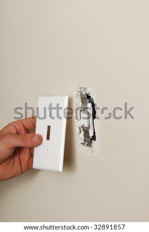An electrician removing a light switch plate