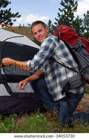 A backpacker zipping up his camping tent
