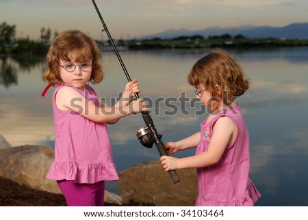 Twin girls fishing at the lake in the evening