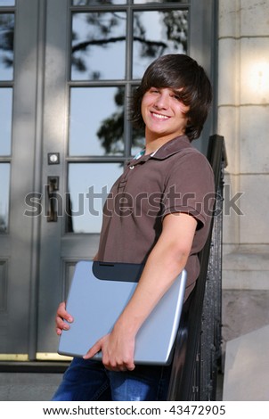 A happy student in front of a school building with a laptop computer