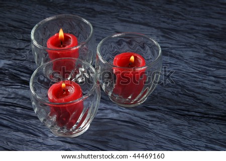 Three votive candles burn in glass holders