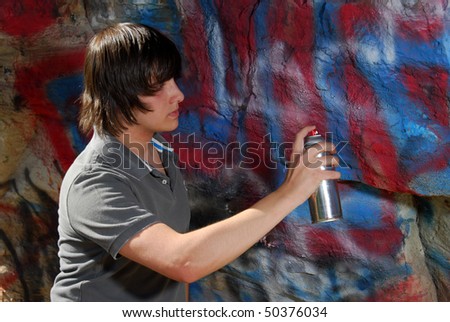 A teenager sprays paint onto a rock formation