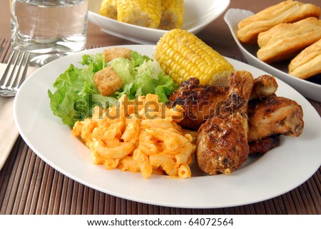 Fried chicken drumsticks with salad and macaroni and cheddar cheese