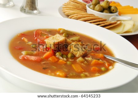 Steaming hot vegetable soup with crackers and cheese for appetizers