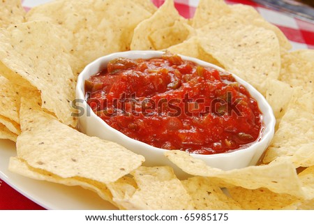 Spicy red salsa with a plate of tortilla chips, focus on the salsa
