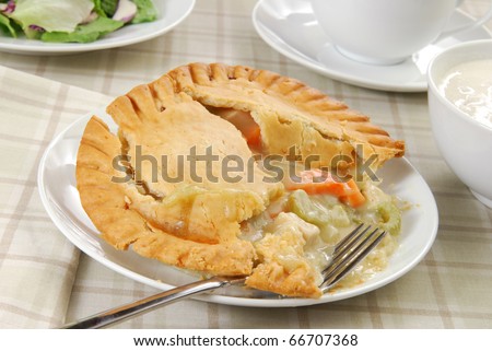 A chicken pot pie with a bowl of clam chowder and a green salad