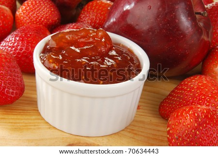A bowl of strawberry-apple jam with fresh apples and strawberries