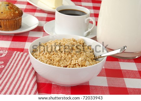 A bowl of granola cereal with a pitcher of milk