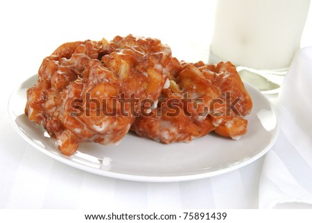 A plate of apple fritters with a glass of cold milk