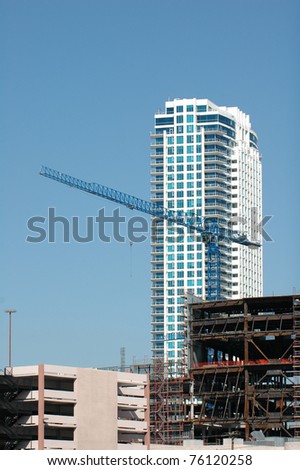A crane on the top of a new building being erected in the downtown area of a city
