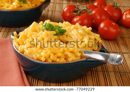 A bowl of macaroni and cheddar cheese and fresh tomatoes