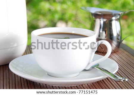 A cup of black coffee with cream on the patio