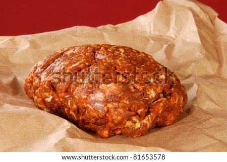 Fresh ground choriso pork sausage on butcher paper with a red background
