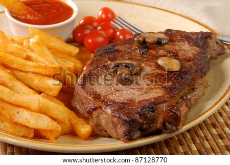 A grilled rib steak with french fries, closeup