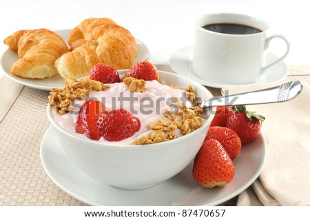 A breakfast of croissants, yogurt, strawberries and black coffee